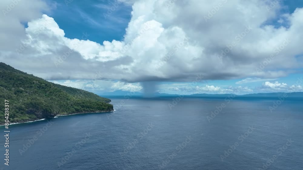 Weh island's northern coast with distant rain, showcasing the lush landscape and vast ocean, aerial view