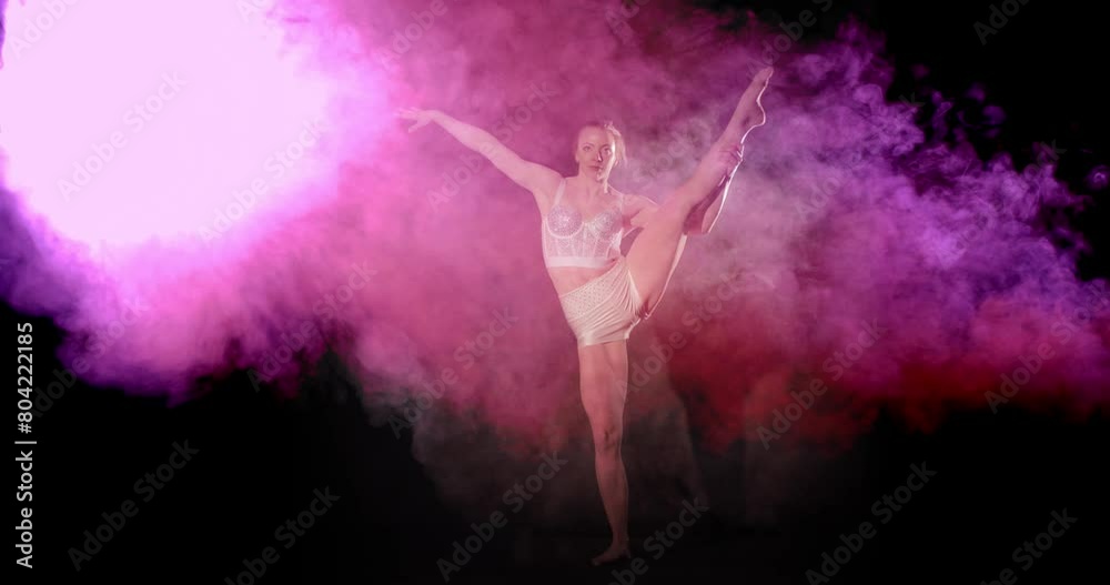 Acrobat shows good balance and does leg hold pose with pink and purple smoke Acrobat shows good balance and does leg hold pose with pink and purple smoke