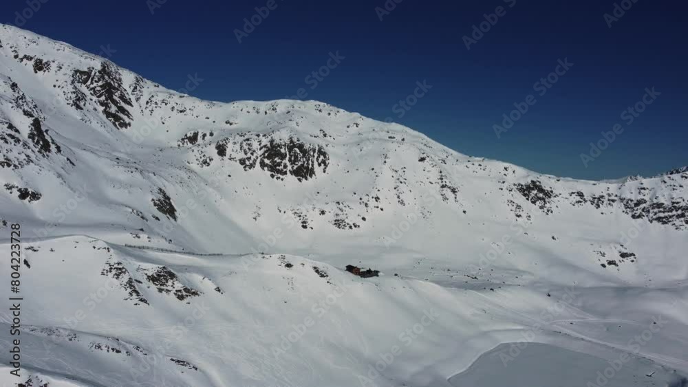 Remote cabin in white snowy mountains in Alps, aerial