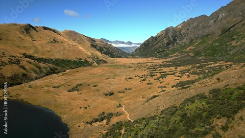 From Moke Lake across the grasslands, foothills and mountains near Queenstown, New Zealand - aerial flyover photo