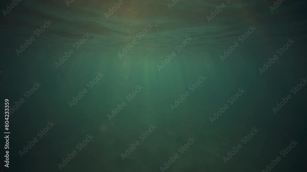Rays of light sparkle down below water surface with golden glow Rays of light sparkle down below water surface with golden glow