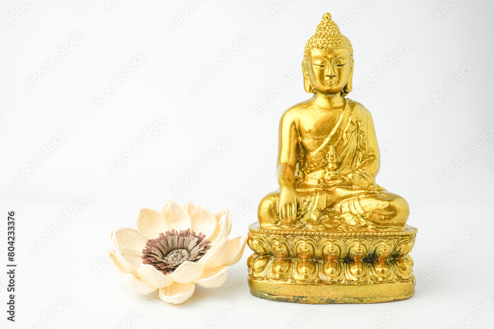 A golden statue of a Buddhist figure meditating decorate with colorful flowers facing the front isolated on white background. Concept for Vesak Day and Enlightenment Day