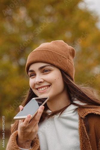 Woman recording voice message on smartphone outdoors 