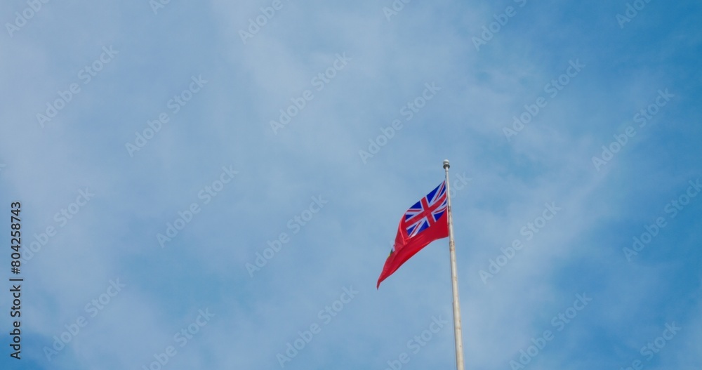 Fluttering British colony flag, vivid against blue sky, symbolizes historic pride, enduring legacy. National emblem waves, reflecting past sovereignties, colonial history. Not official Flag of Canada Fluttering British colony flag, vivid against blue sky, symbolizes historic pride, enduring legacy. National emblem waves, reflecting past sovereignties, colonial history. Not official Flag of Canada