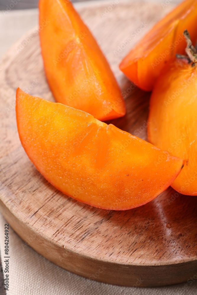 Pieces of delicious persimmons on wooden board, closeup