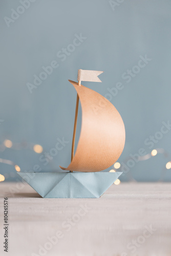 Segelboot aus Papier mit Mast aus Holz auf blauen Hintergrund - geeignet für Themen wie Aufbruch, Religion, Kommunion, Konfirmation, Abenteuer photo