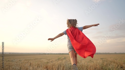 kid superhero run. girl daughter happy family a dream concept. baby girl superhero run in red cape at sunset. portrait child superhero in the park. strength fantasy lifestyle concept