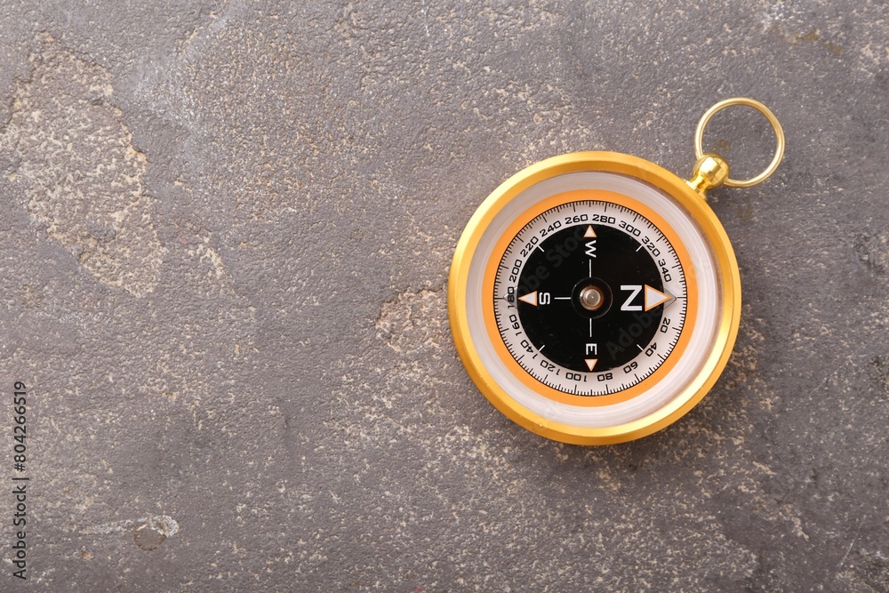 One compass on grey textured background, top view. Space for text One compass on grey textured background, top view. Space for text