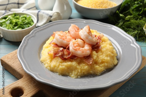 Plate with fresh tasty shrimps, bacon and grits on light blue wooden table