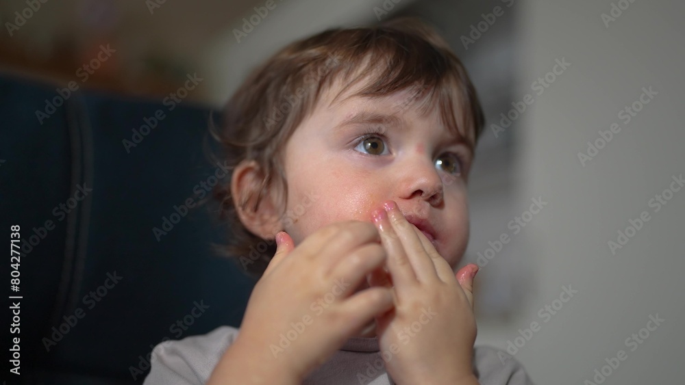 little child resting at home. happy and full of joy childhood, children's dream concept. a small girl are sitting on lifestyle a blue sofa attentively watching cartoons on TV and eat apples little child resting at home. happy and full of joy childhood, children's dream concept. a small girl are sitting on lifestyle a blue sofa attentively watching cartoons on TV and eat apples