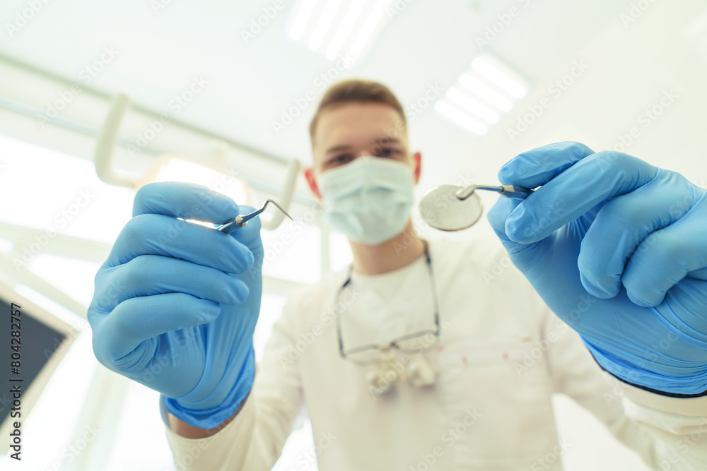 dentist bends over the patient and is about to begin the examination dentist bends over the patient and is about to begin the examination
