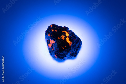 natural yooperlite gem stone in uv light on the white background photo