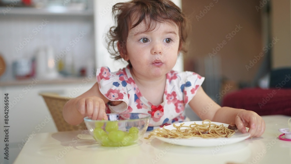 the girl eats at the table. happy family child dream concept. girl sits indoors at a white table and eats food with food her hands holding an apple in his hand. child's lifestyle the girl eats at the table. happy family child dream concept. girl sits indoors at a white table and eats food with food her hands holding an apple in his hand. child's lifestyle