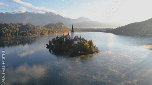 Flight around (360-degree Video) of Bled Island (Blejski otok) with Pilgrimage church of the Assumption of Mary and Bled on Lake Bled at clear autumn morning with light fog, Upper Carniola, Slovenia photo