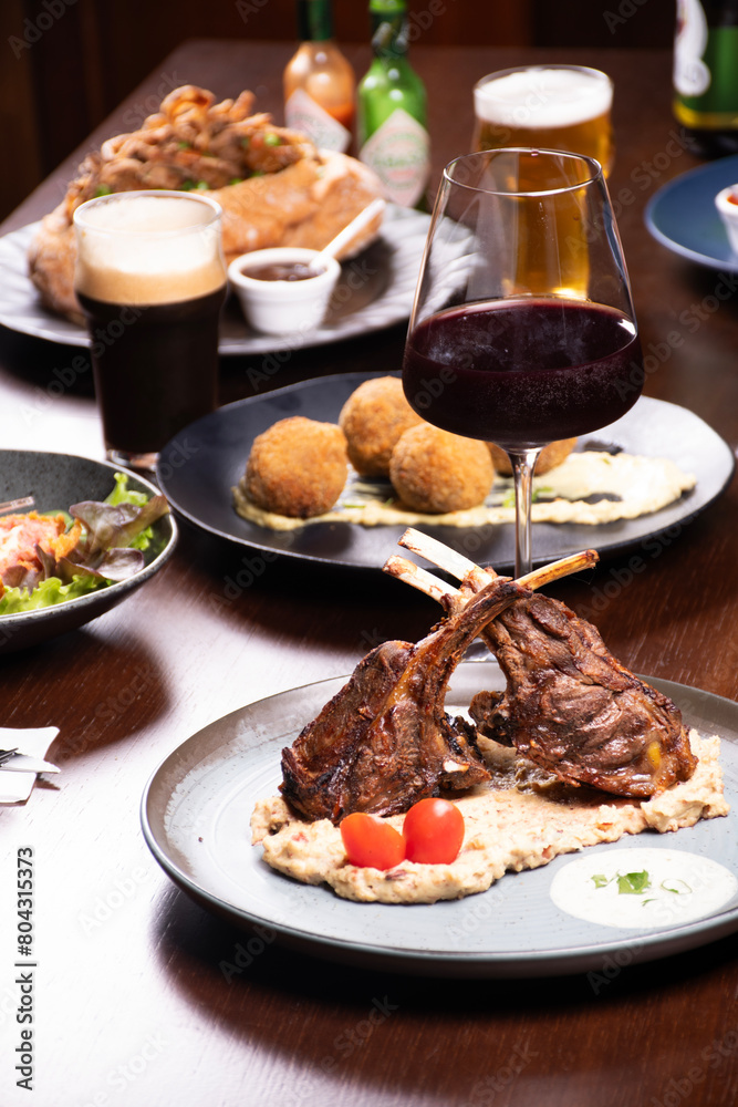 banquet table dinner in steakhouse with rack of lamb on mashed potatoes and glass of red wine banquet table dinner in steakhouse with rack of lamb on mashed potatoes and glass of red wine