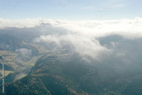 Aerial view of fluffy clouds over mountain forest