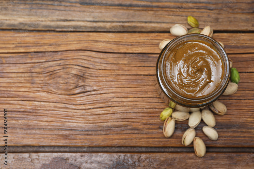 Tasty pistachio nut paste in jar on wooden table, top view. Space for text Tasty pistachio nut paste in jar on wooden table, top view. Space for text