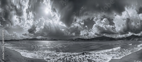 Black and white panorama of the sea, with dark clouds overhead, a distant view of mountain photo