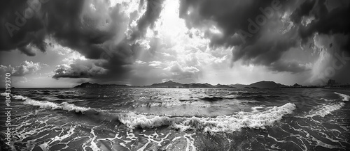 Black and white panorama of the sea, with dark clouds overhead, a distant view of mountain photo