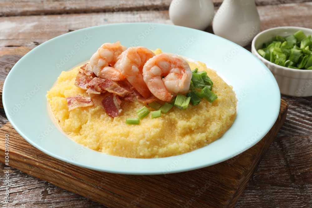 Plate with fresh tasty shrimps, bacon, grits and green onion on wooden table, closeup Plate with fresh tasty shrimps, bacon, grits and green onion on wooden table, closeup