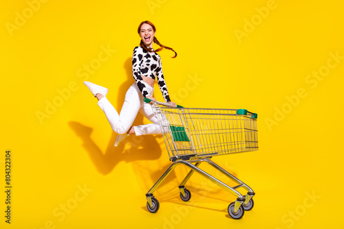 Full length photo of excited cheerful woman wear cow skin print top jumping enjoying shopping isolated yellow color background © deagreez