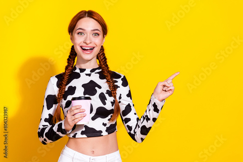 Photo of excited funky woman wear cow skin print top drinking coffee pointing empty space isolated yellow color background