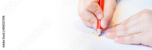 Close-up of a child s hands drawing with colored pencils. Children s creativity and development  fine motor skills  learning to write and draw. Banner with free space for text