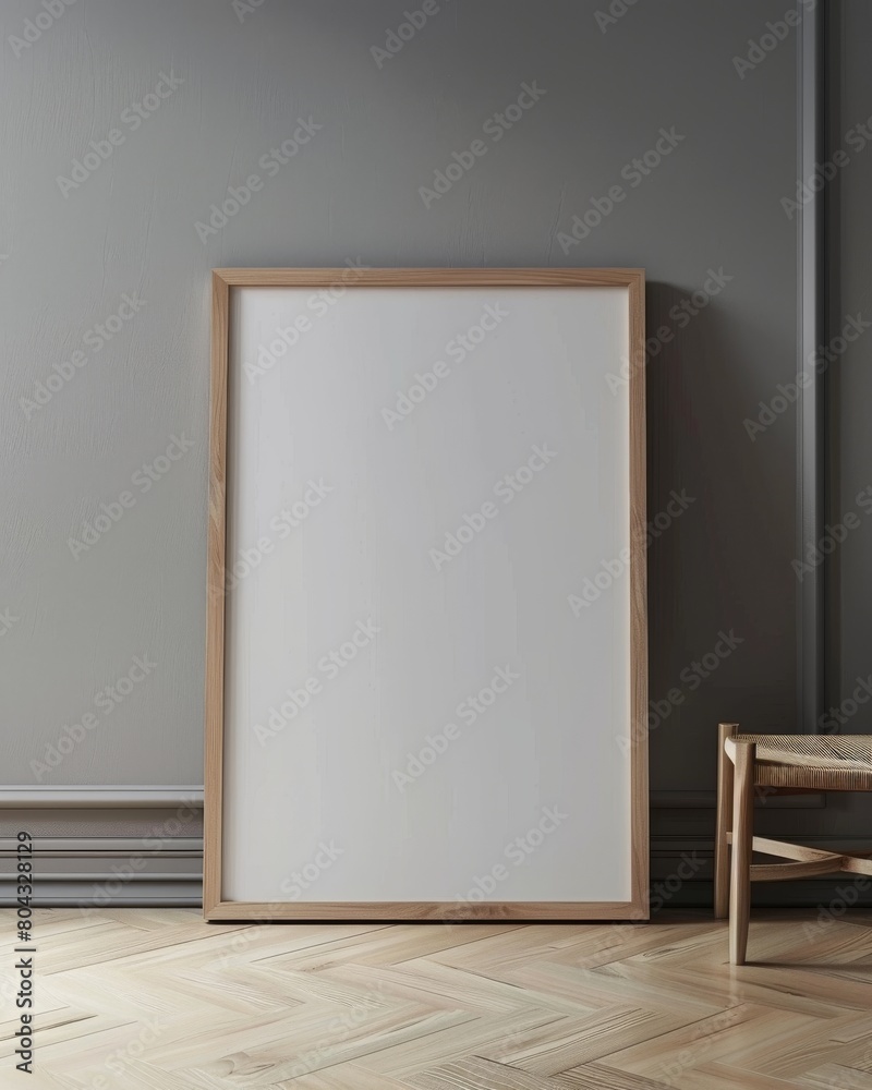 A wooden frame mockup standing on the wooden floor against the gray wall in the interior of the room. There is a wooden chair standing next to it. A wooden frame mockup standing on the wooden floor against the gray wall in the interior of the room. There is a wooden chair standing next to it.