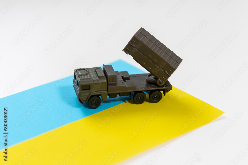 Naklejka premium Artillery rocket system are aimed to the sky and soldier at sunset with Ukrainian flag. Multiple launch rocket system.