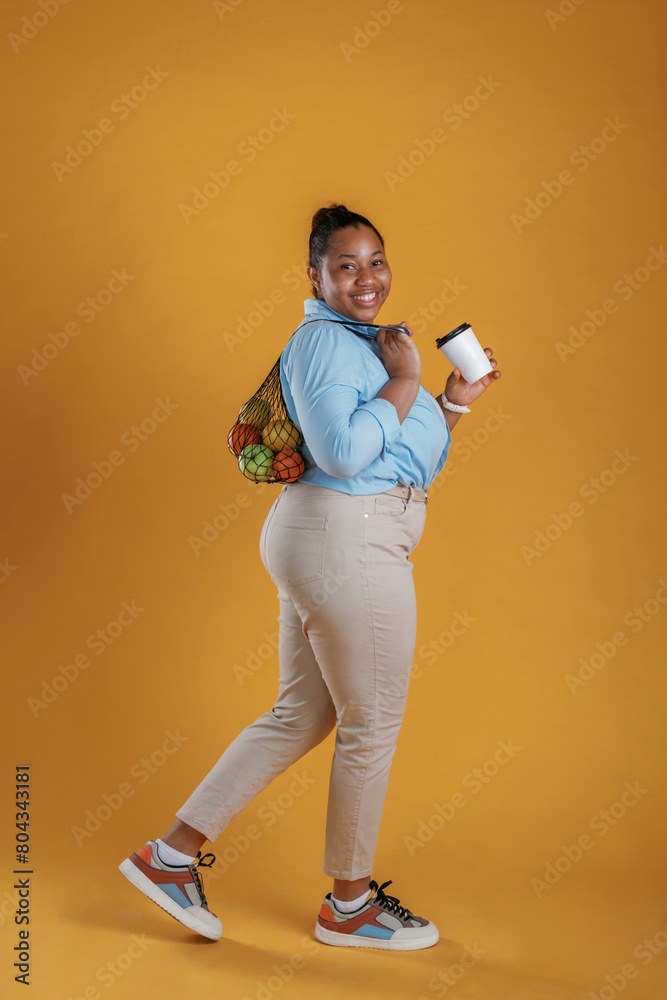 Fresh coffee. Customer with bunch of fruits in the bag, holding. African American woman is in the studio Fresh coffee. Customer with bunch of fruits in the bag, holding. African American woman is in the studio
