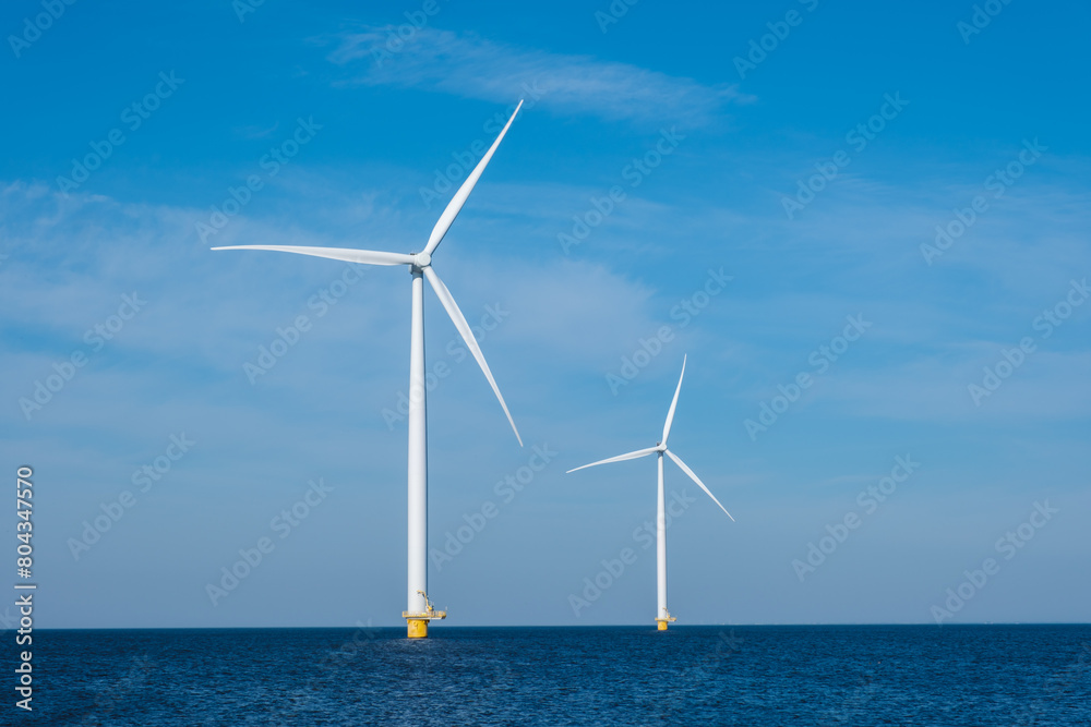 Three colossal wind turbines stand tall and majestic in the vast expanse of the ocean, harnessing the powerful energy of the wind to generate electricity