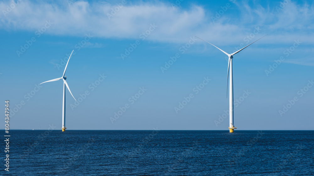 Two wind turbines stand tall in the middle of the ocean, harnessing the power of the wind to generate renewable energy for the Netherlands Flevoland region