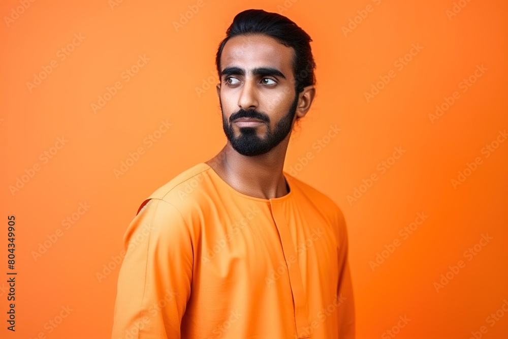 Fototapeta premium A man with a beard and dark hair is wearing an orange shirt