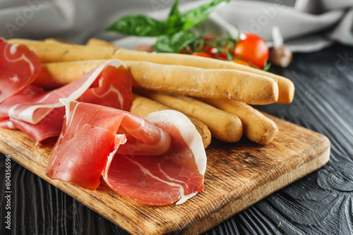 crispy grisini with prosciutto on a black wooden rustic background photo