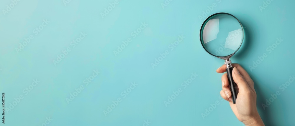 Obraz premium Biology business working dedective searching concept banner - Close up of a woman's hand holding a magnifying glass lens in her hand, isolated on blue background
