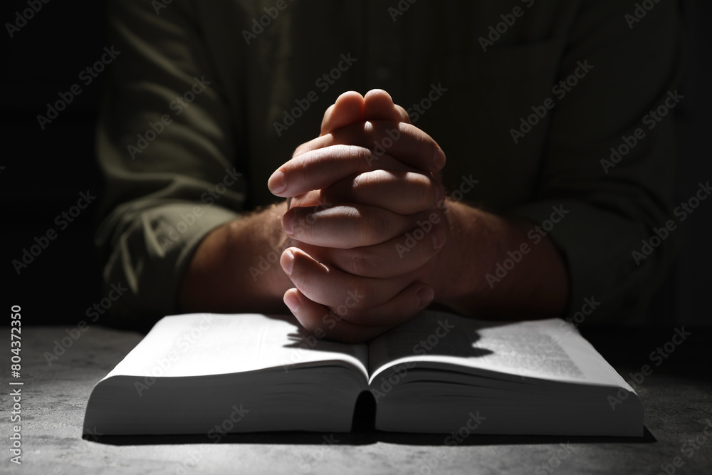 Obraz premium Religion. Christian man praying over Bible at table, closeup