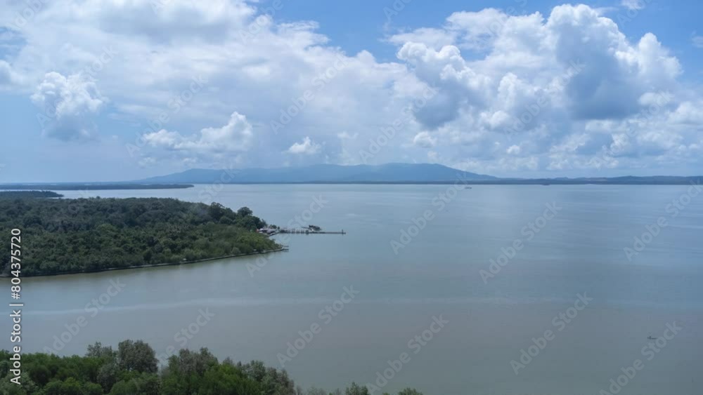 Time lapse aerial view of the pier of the bird island tourist spot filled with mangrove forests with mountains and clouds in the background Time lapse aerial view of the pier of the bird island tourist spot filled with mangrove forests with mountains and clouds in the background