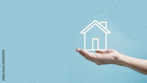 A hand holding an icon of a house on a light blue background
