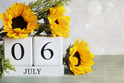 Virtually Hug a Virtual Assistant Day. White wood calendar blocks with the date July 6th and beautiful sunflower bouquet with bokeh. Selective focus with blurred background. 