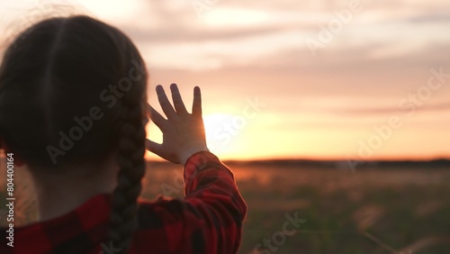 Girl dreamily reaches for sun with hand. Symbolism striving for light wisdom spiritual enlightenment knowledge self-development aspirations. Expectation of miracle dreams inspiration of young child.