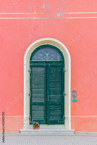 Pink house with a green door in Marina di Pisa, Italy