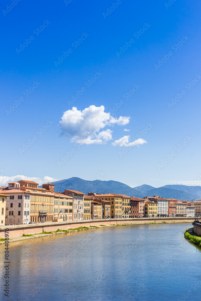 Colorful houses with mountain backdrop at the Arno river in Pisa, Italy