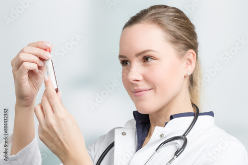 young female doctor is checking a blood probe in her hand