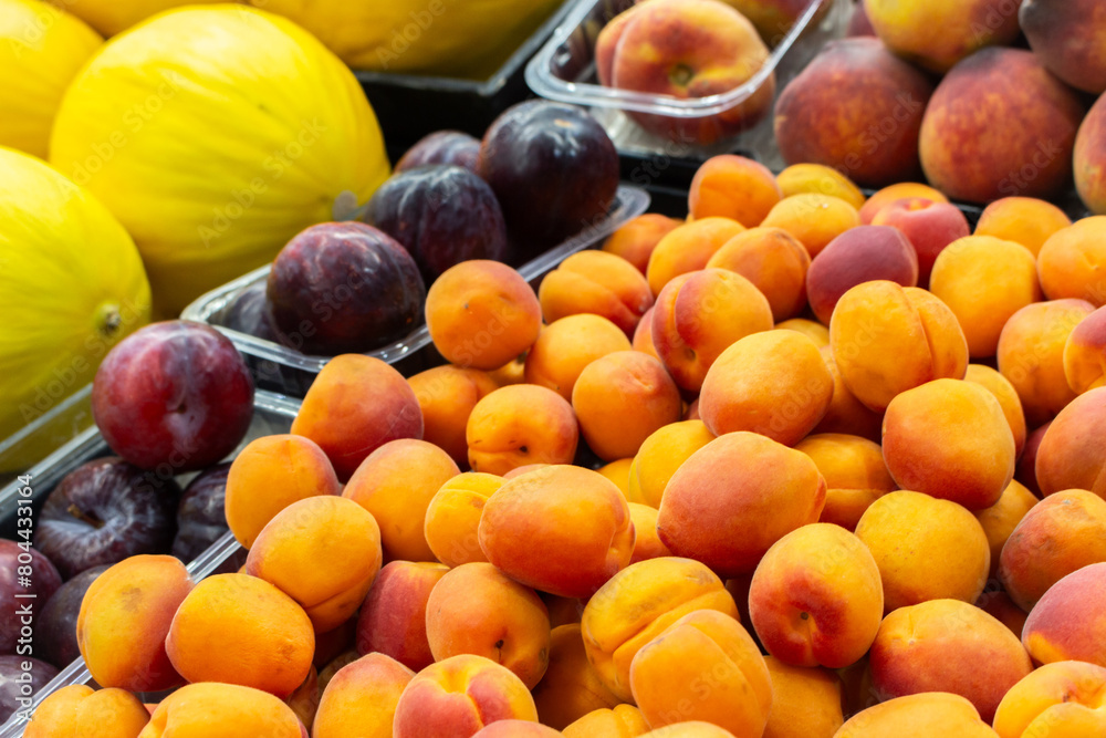Apricots, plums, peach and melon on market stall. Heap of juicy fruits. Summer harvest. Healthy eating. Vitamins and antioxidant. Fruit market. Local harvest. Organic peach and apricot.