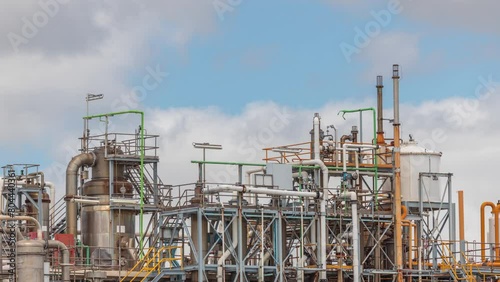 Distillation Columns and their process equipment of hydrogen plant timelapse with clouds on a background. Many pipes and tanks of industrial factory against a sky photo