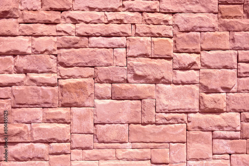 Abstract geometric background of wall lined with decorative stone tiles. Toned in pink clolor. Close up.