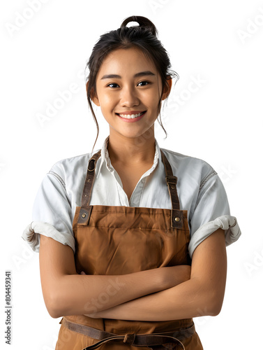 A young woman barista or entrepreneur woman with a radiant face and warm smile, wearing white shirt and apron, stands with folded hands in front of a white background.