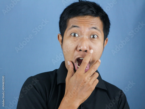 Shocked and surprised face of Asian man in isolated on blue background. photo