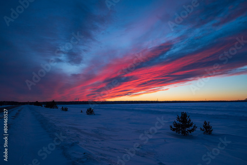Snowy field with a sunset creating a red sky afterglow in the natural landscape