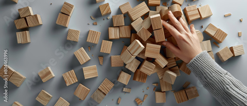 A person's hand picking up wooden blocks from a pile. photo